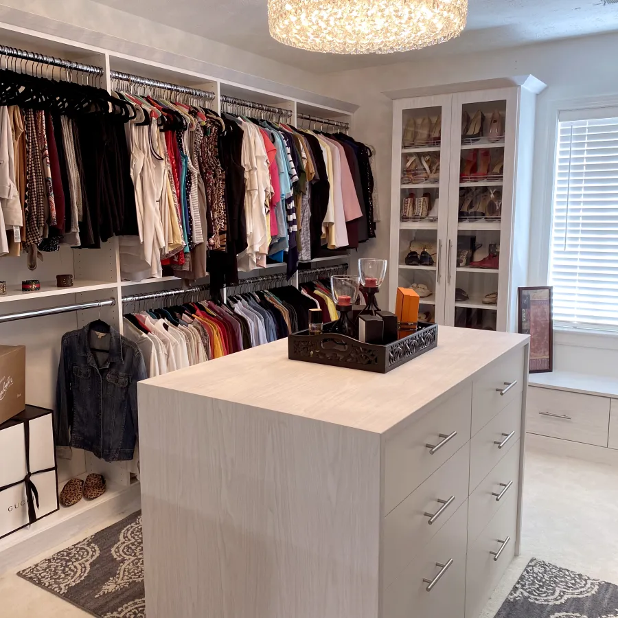 a room with a white cabinet and a white counter with a white shelf with clothes on it