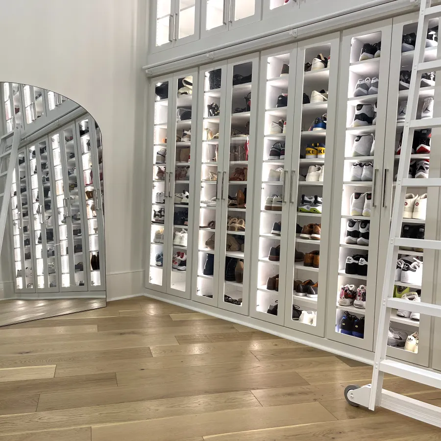 a white shelving unit with many bottles of perfume