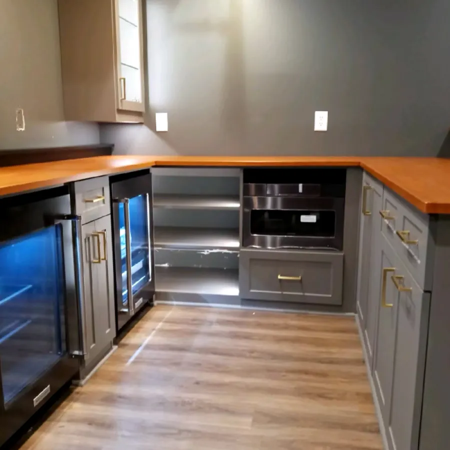 Modern kitchen with gray cabinets, wooden countertops, mini fridge and wood laminate flooring.