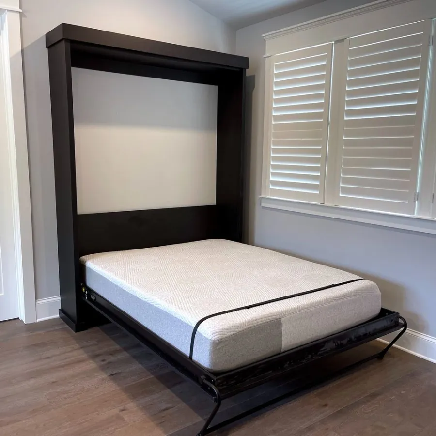 Modern Murphy bed with white mattress in a bright room with wood floors and white shutters