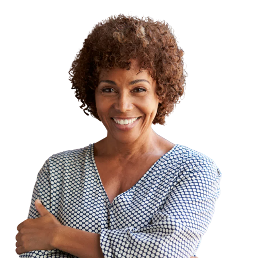 Smiling middle-aged woman with curly hair wearing a patterned blouse with arms crossed confidently.