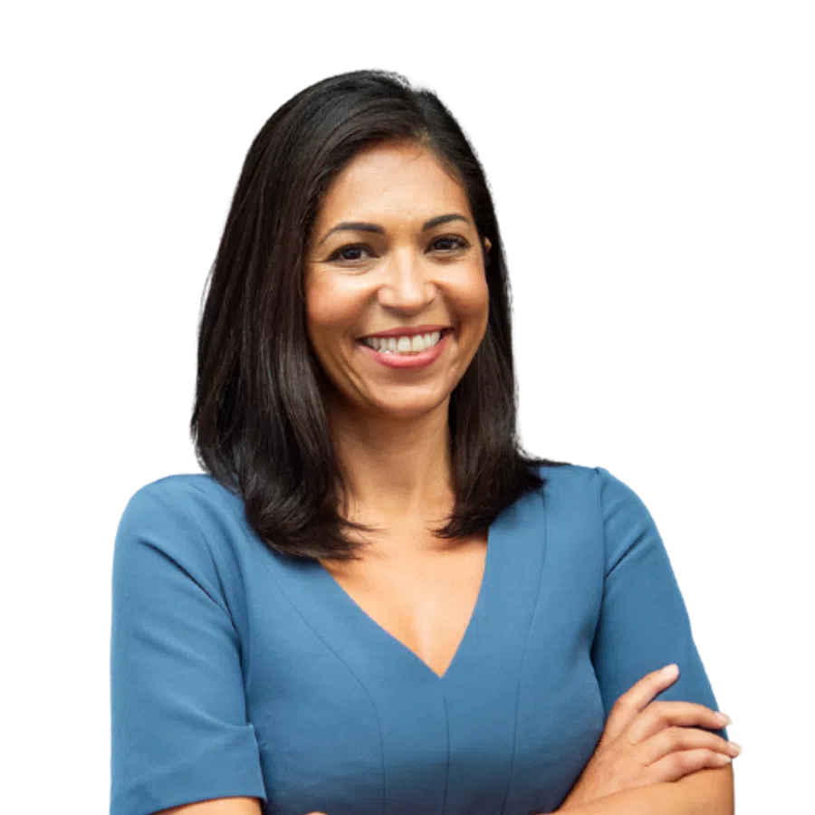 Confident woman with crossed arms wearing a blue dress and silver wristwatch smiling at the camera.