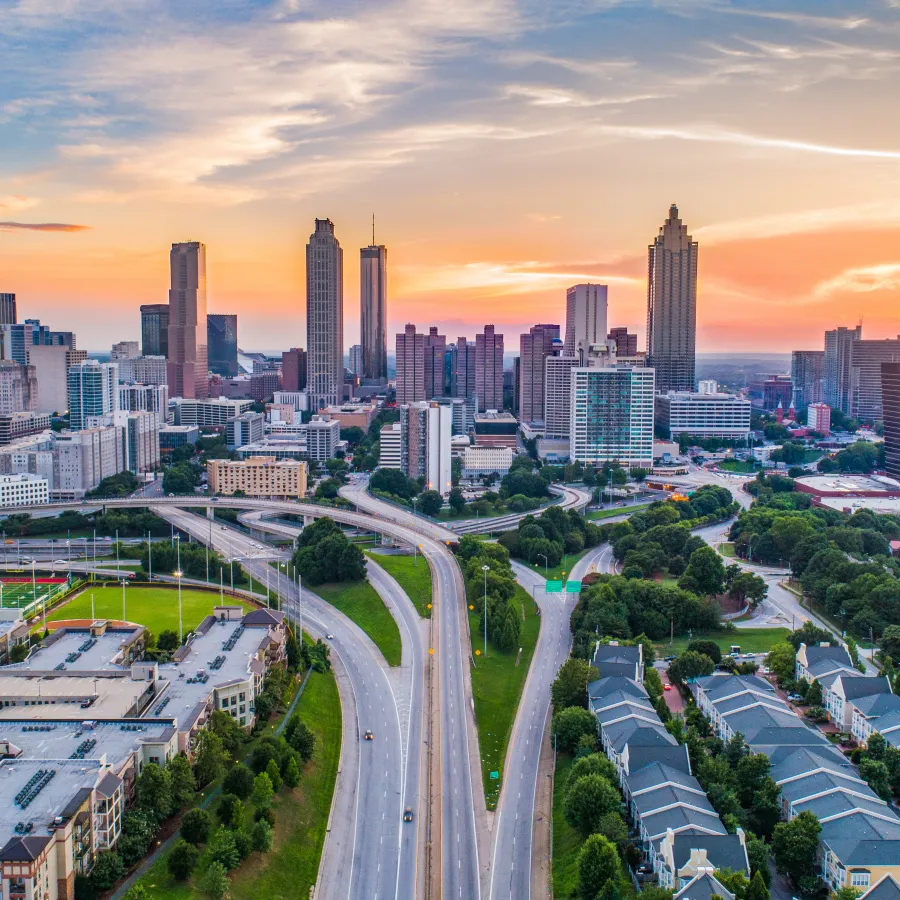 Aerial view of Atlanta skyline at sunset with highways and buildings bathed in golden light.
