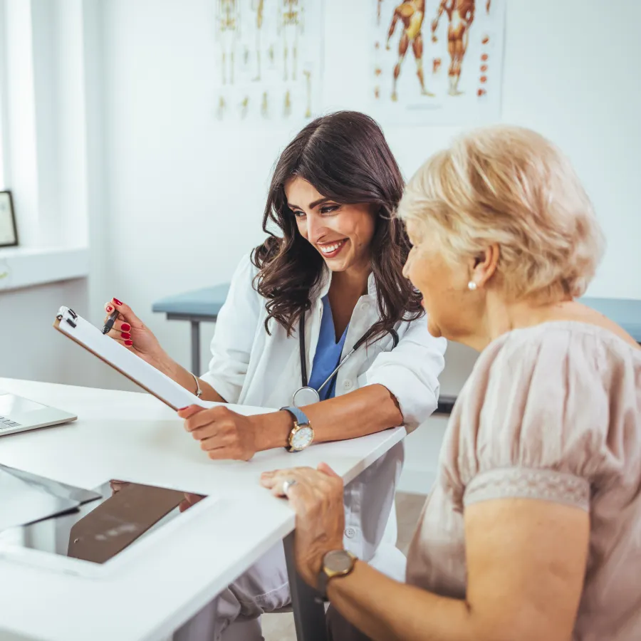 Doctor discussing medical results with elderly female patient in a bright clinic office.
