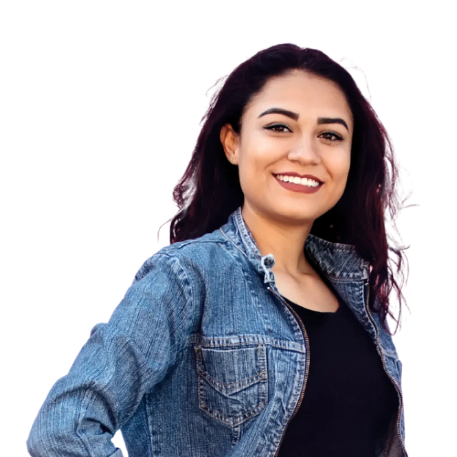 Smiling young woman with dark hair wearing a denim jacket and black top, posing confidently with hand on hip