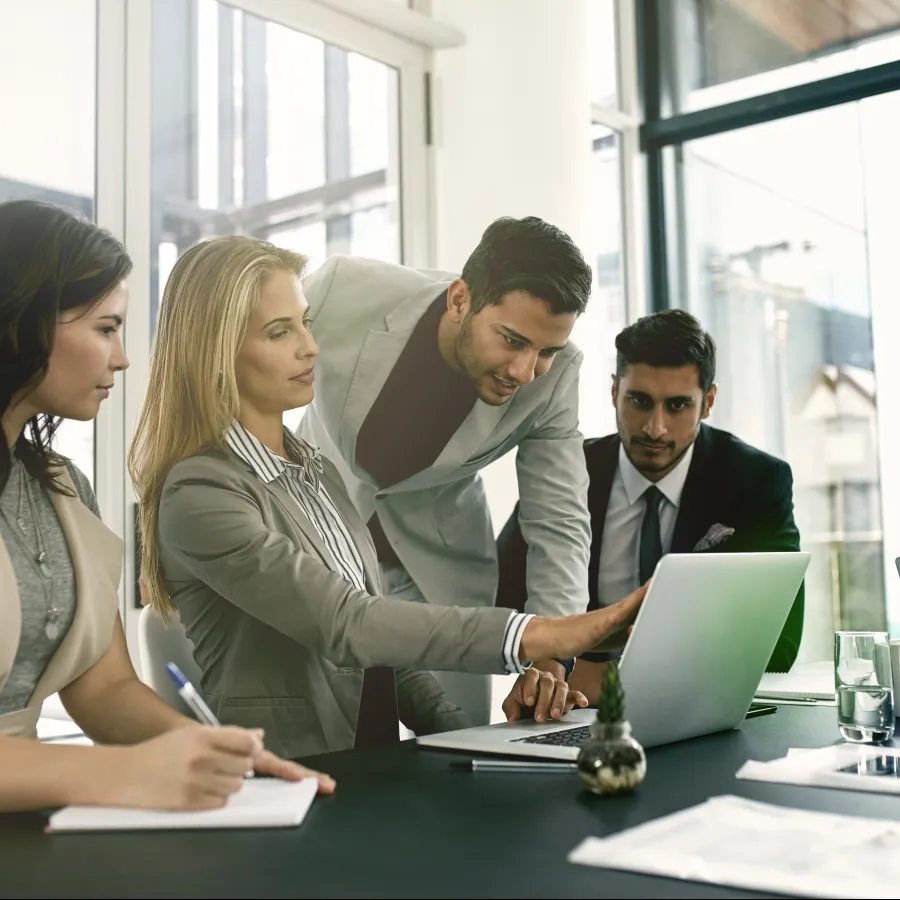Business meeting with professionals discussing strategy around a laptop.