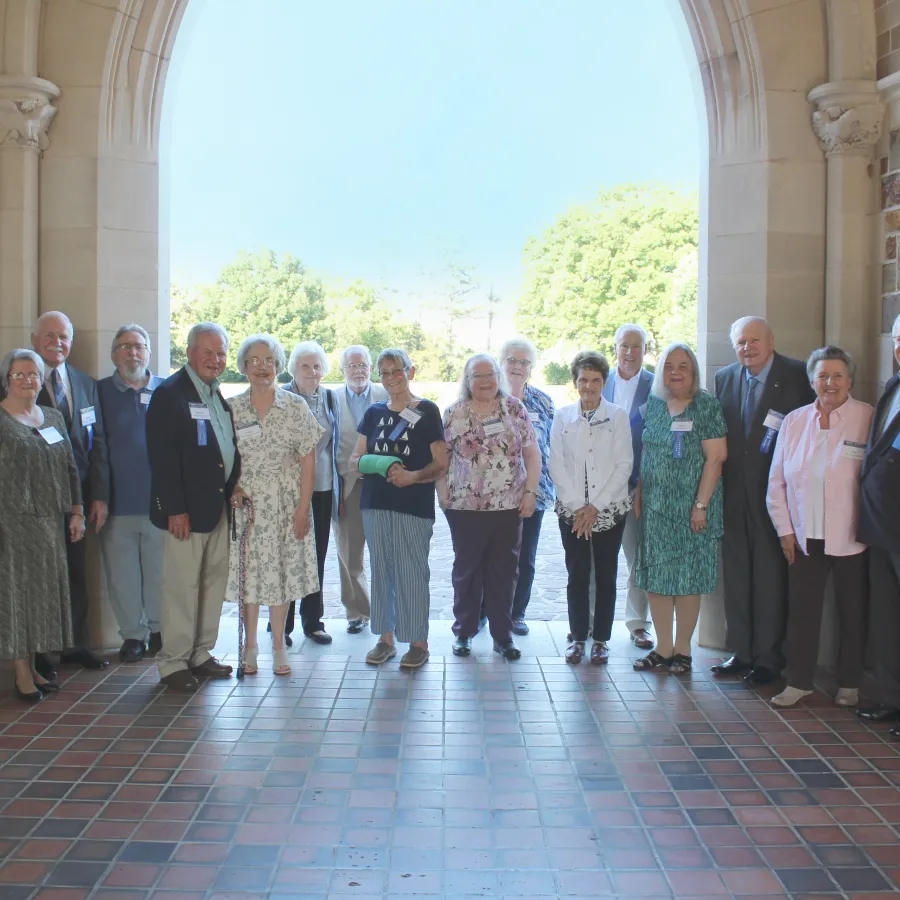 Group of Berry College alumni standing under an archway during a reunion event on a sunny day.