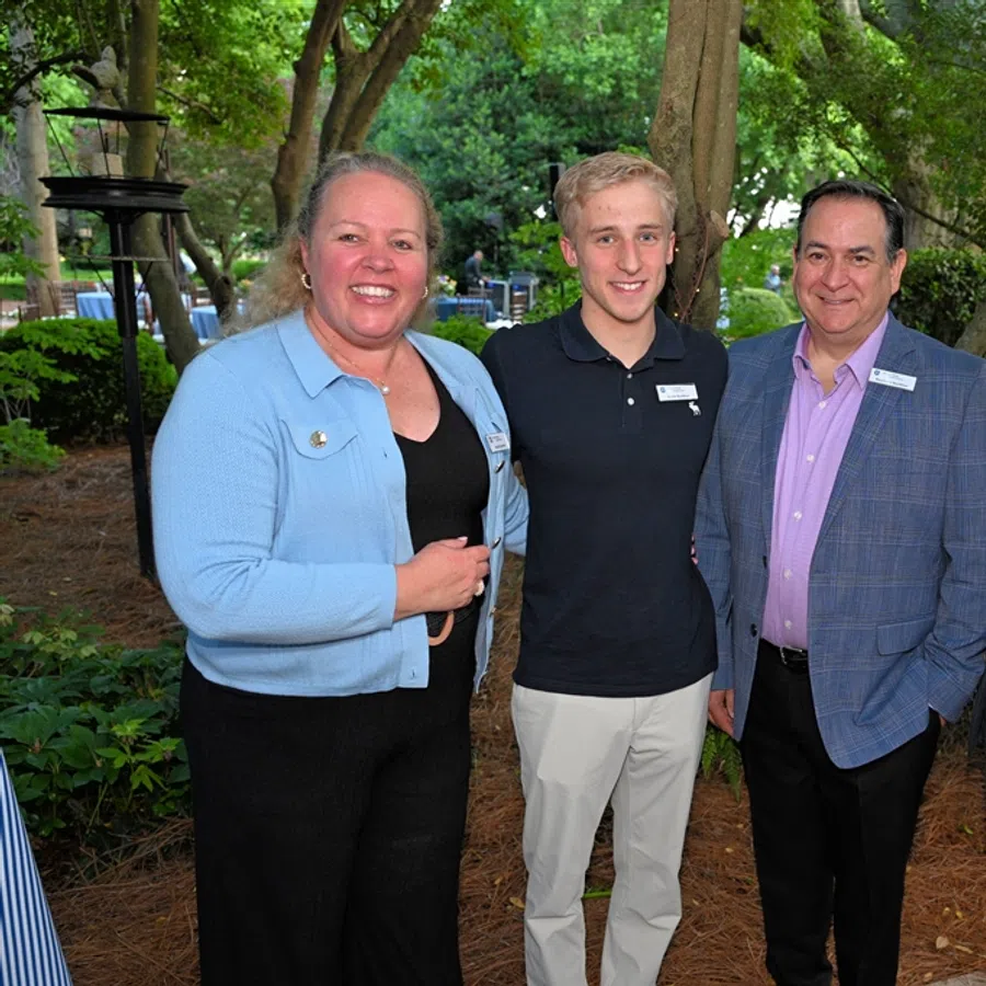 Four diverse professionals smiling and posing together outdoors in a lush garden setting.