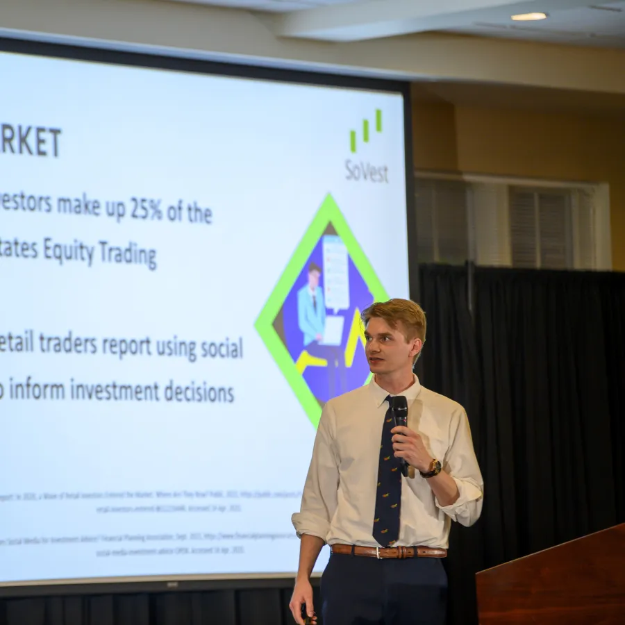 Young man in white shirt gives presentation on retail investors and social media trends in equity trading.