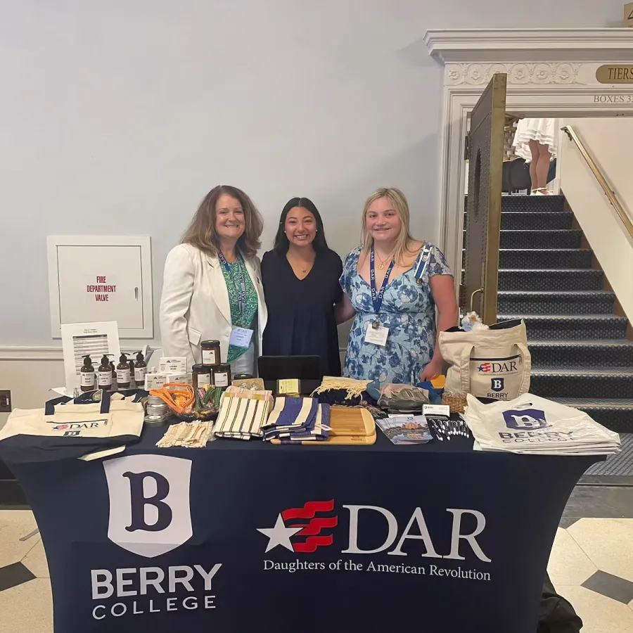 a group of women standing behind a table with food and drinks