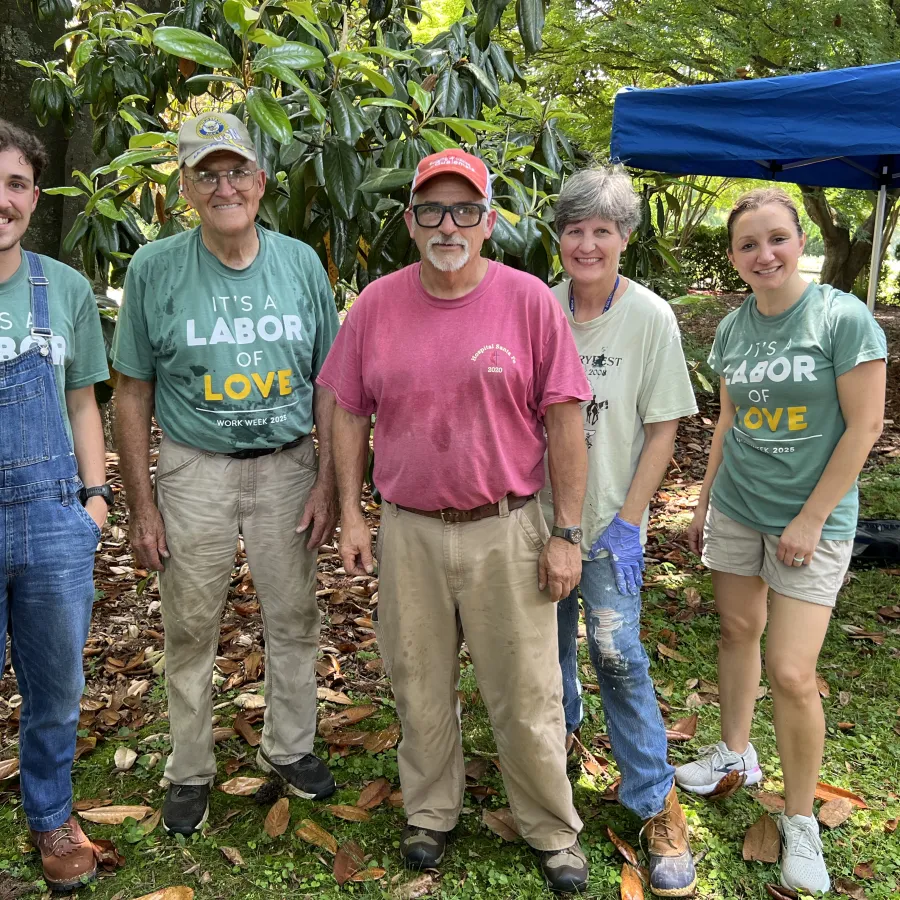 Group of five volunteers standing outdoors in casual clothes during a community work event.