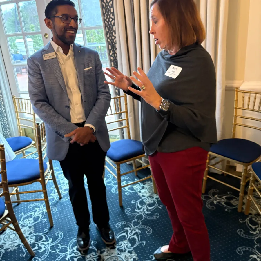 Two professionals engaged in lively conversation in a light-filled room with patterned carpet and chairs