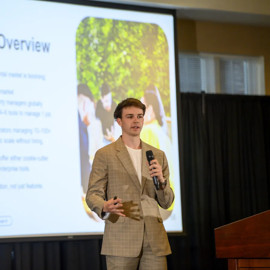 Young man in a plaid suit presenting a business market overview with projected growth and competition analysis