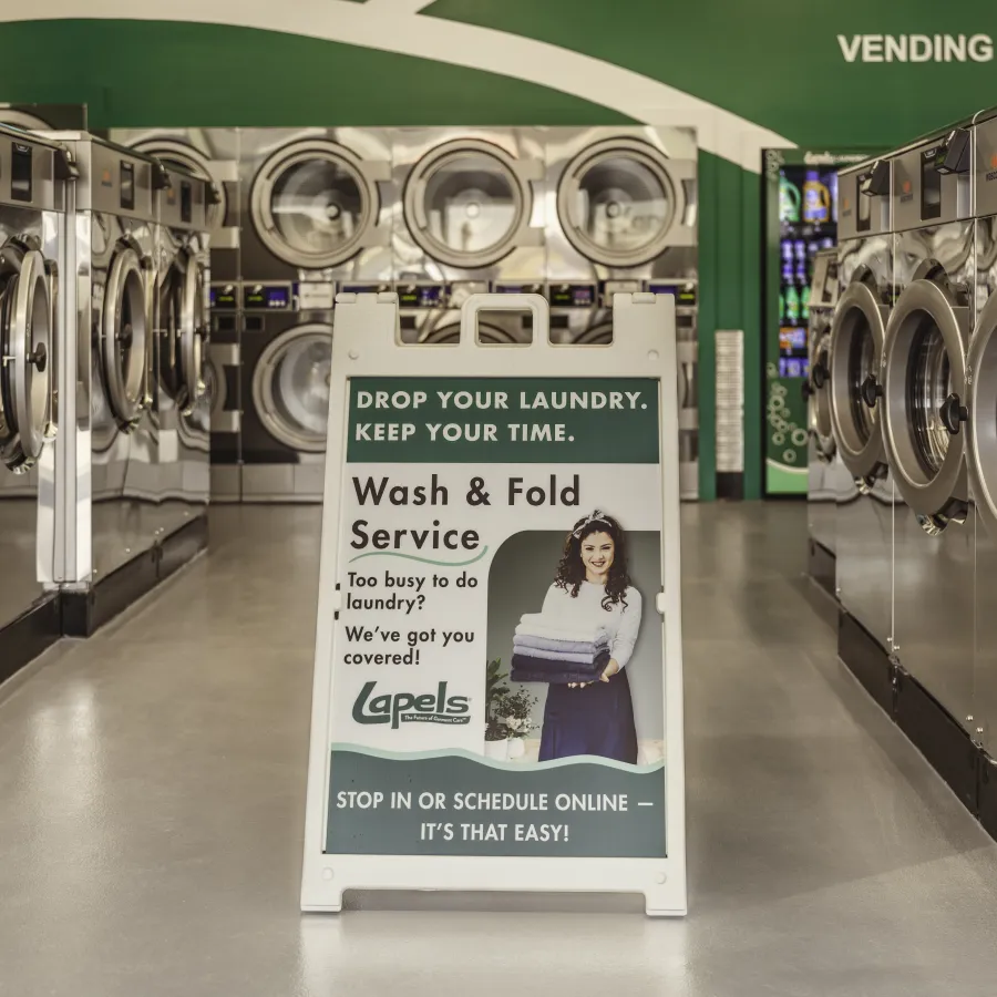 Interior of laundromat with rows of washing machines and a sign advertising wash and fold service.