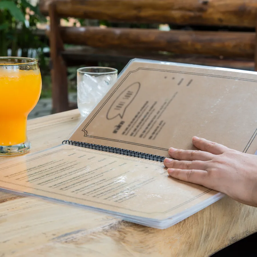 A person reading a Spiral Bound restaurant Menu