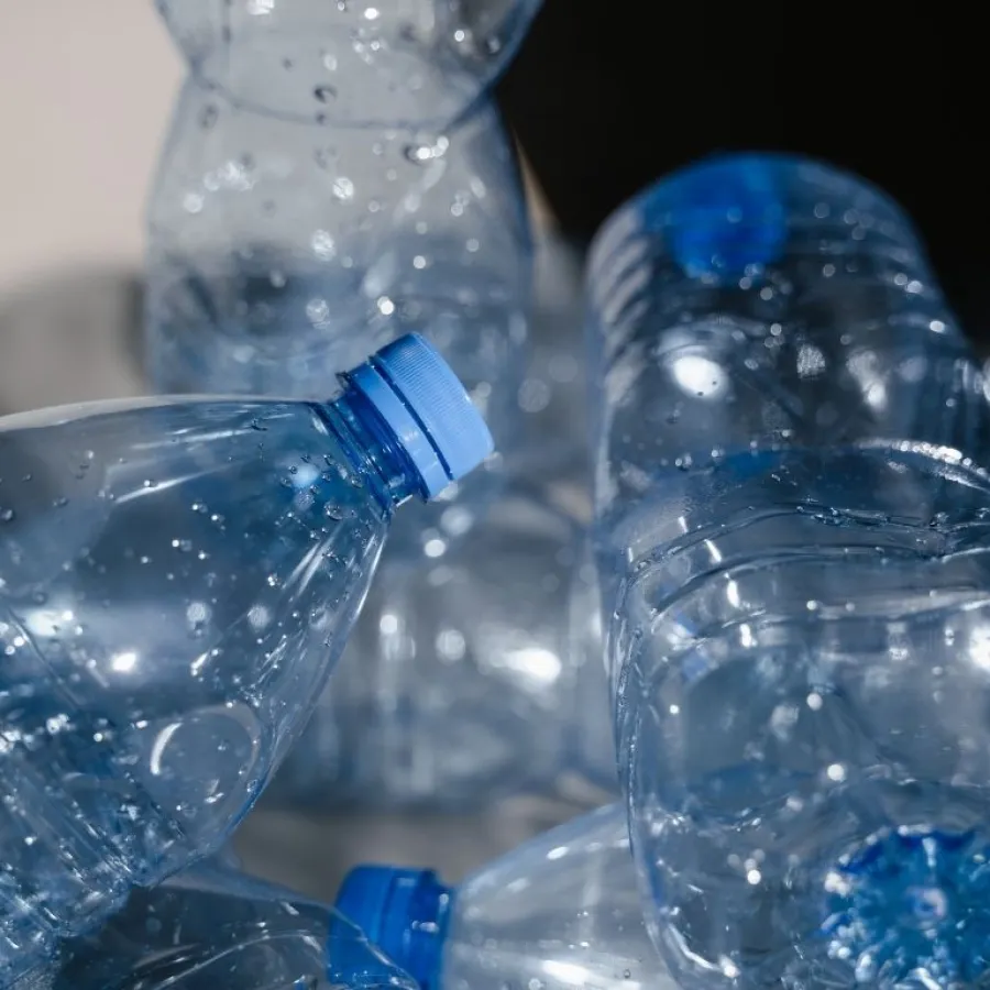 Close-up of several empty clear plastic water bottles with blue caps and water droplets on them.