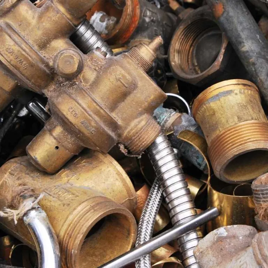 Close-up of old brass plumbing parts and fittings mixed with metal pipes and flexible hoses.
