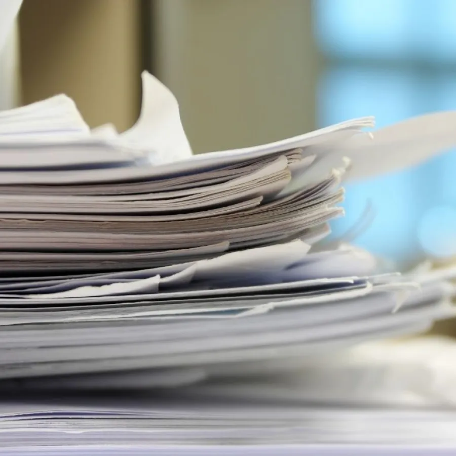 Close-up of a large stack of disorganized papers with blurred background in an office setting
