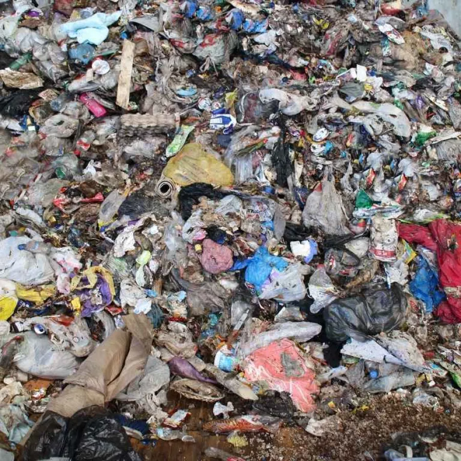 Large heap of mixed household garbage pile including plastics, papers, and organic waste in a landfill.