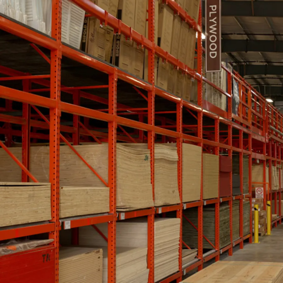 Warehouse storage racks filled with plywood sheets and boxes in an organized industrial facility interior.