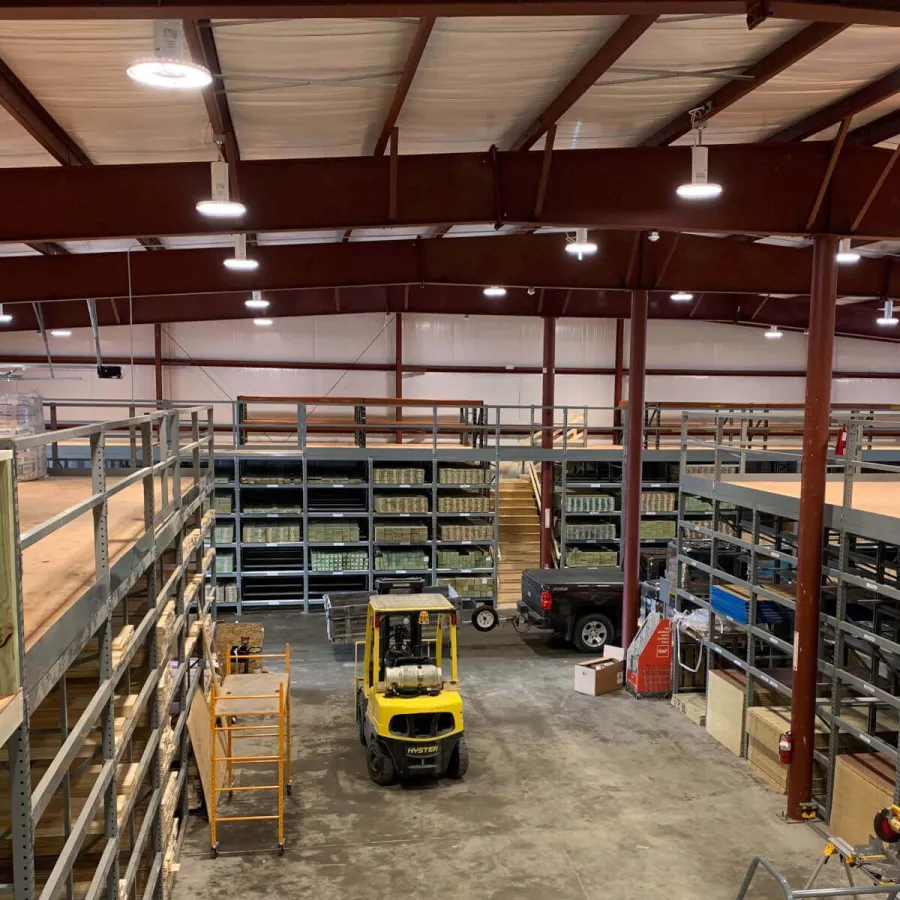 Interior view of a warehouse with metal shelving, a yellow forklift, and stacked inventory under bright lights