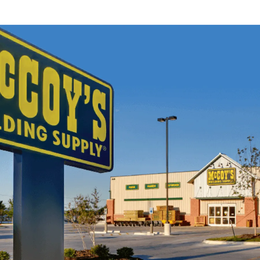McCoy's Building Supply store exterior and large yellow and blue sign in a clear sky parking lot.