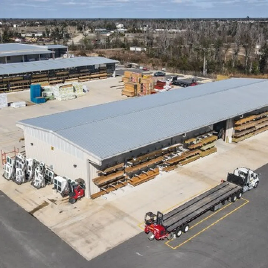 Aerial view of a large outdoor building materials yard with stacks of lumber and forklifts.