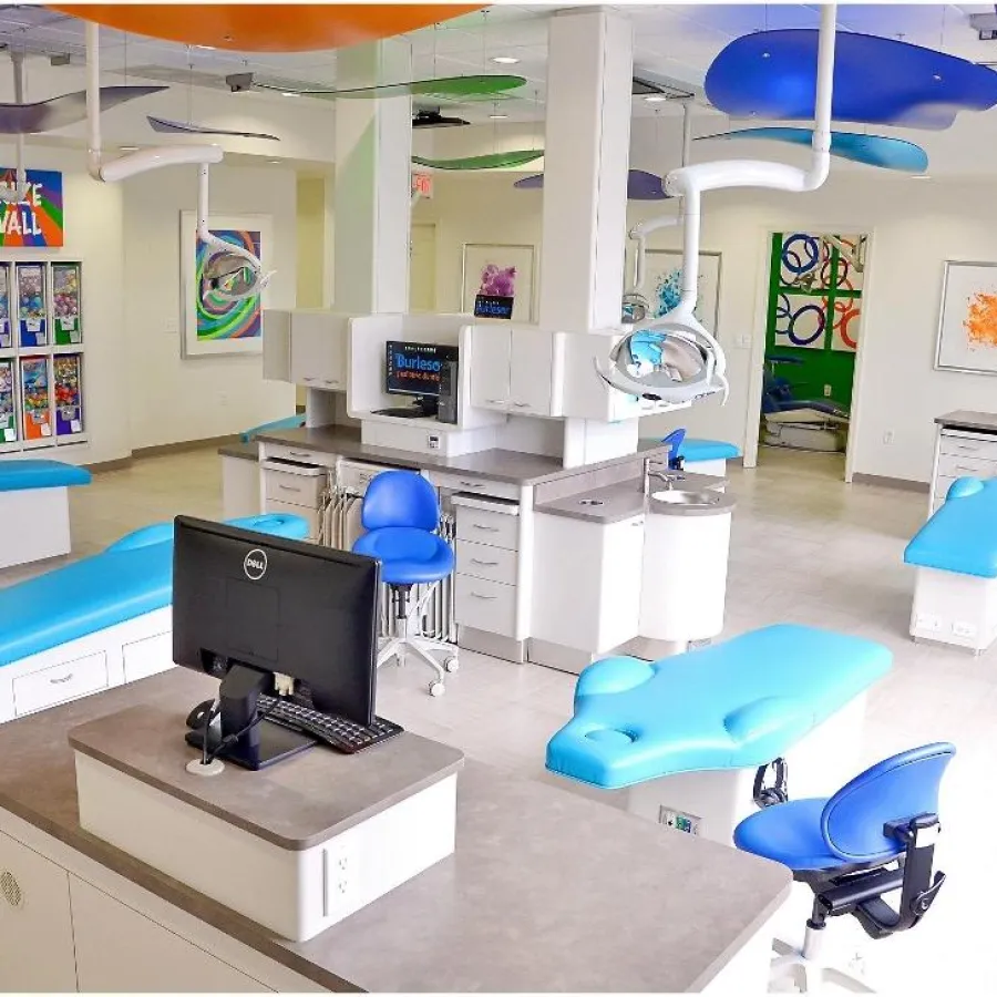 Bright orthodontic clinic with blue dental chairs, modern equipment, and colorful wall art in a spacious room