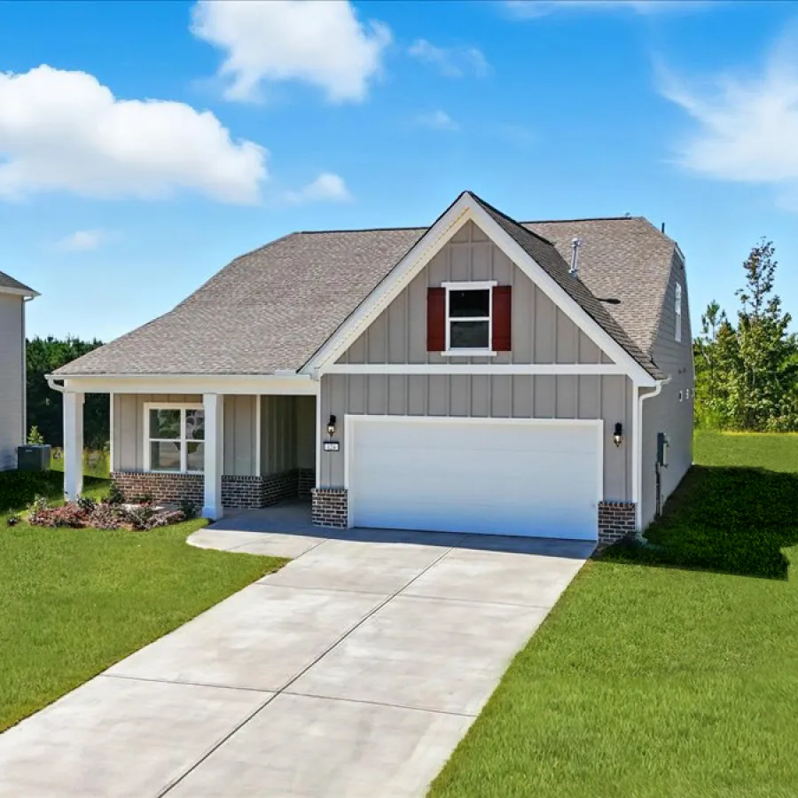 Modern two-story house with gray siding, white garage door, and green lawn under a blue sky with clouds.