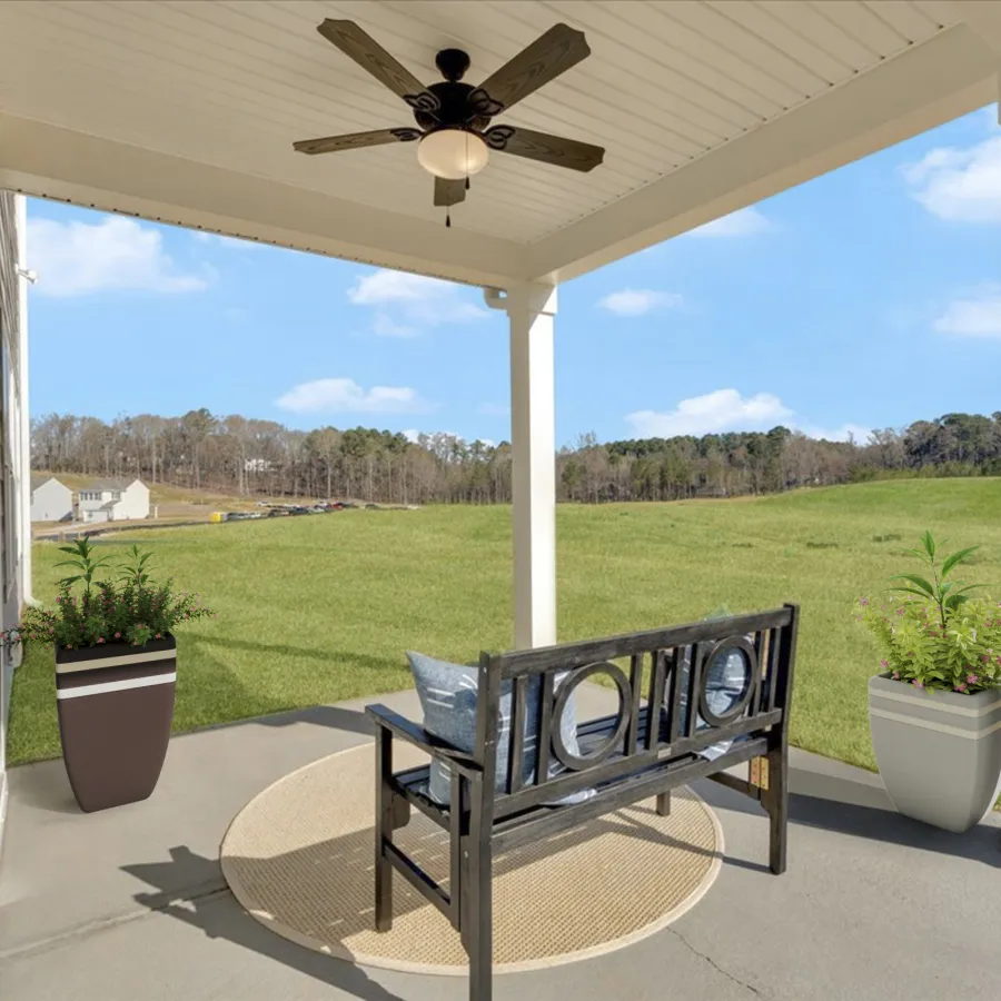 Cozy outdoor porch with seating, fan, and potted plants overlooking a green landscape.