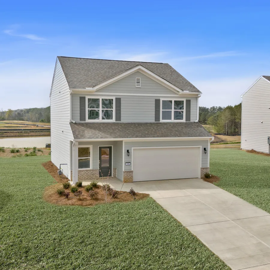Modern two-story house with a driveway, green lawn, and blue sky in the background.
