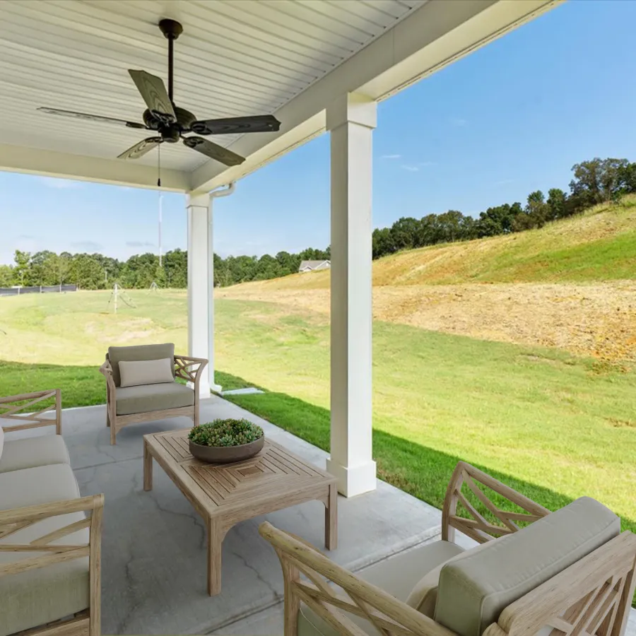 Covered patio with cushioned wooden seating, coffee table, ceiling fan, and grassy hillside view under blue sky
