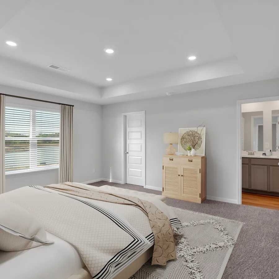 Bright modern bedroom with large bed, beige curtains, wooden dresser, and doorway leading to a bathroom.