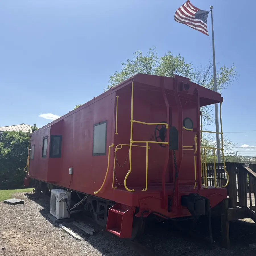 Bright red caboose on display with an American flag waving in the background.