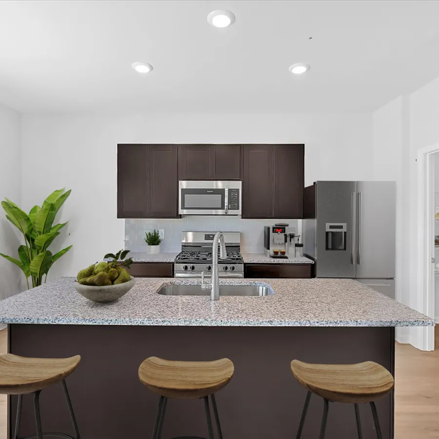 Modern kitchen with dark cabinets, stainless steel appliances, granite island, three stools, and pantry door open.