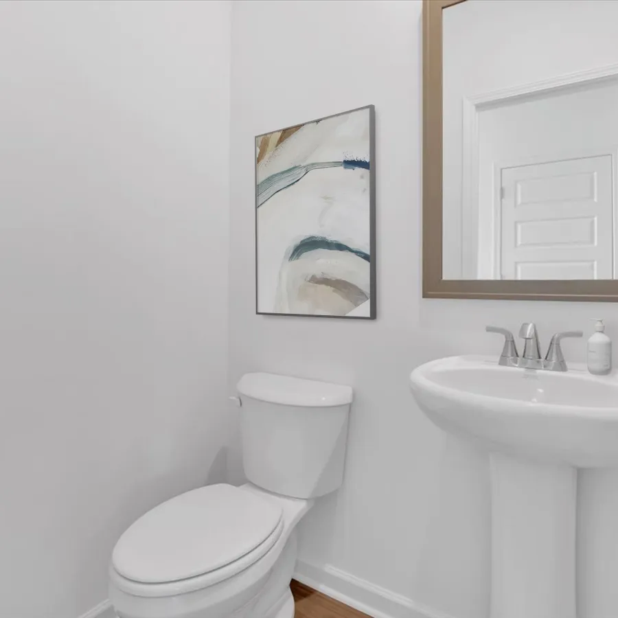 Modern bathroom featuring a toilet, sink, and abstract wall art in a bright, minimalist setting.