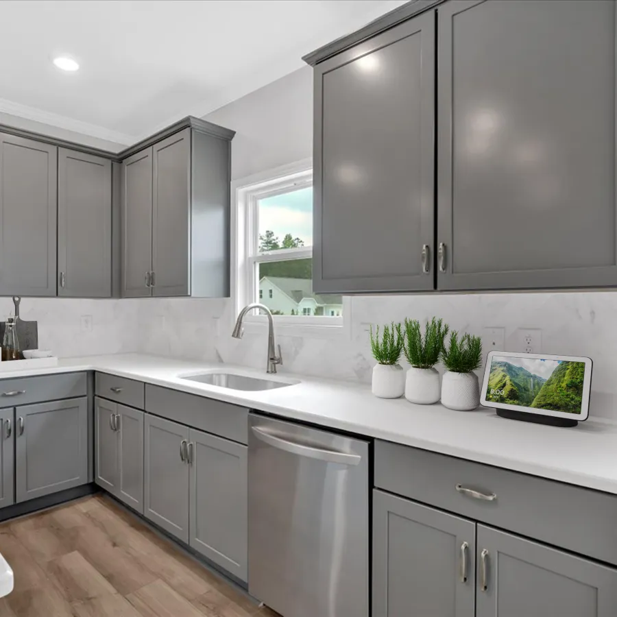 Modern kitchen with gray cabinets, white countertops, stainless steel appliances, and small potted plants by the window.