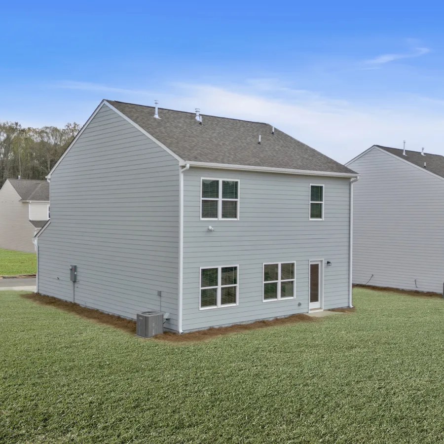 Modern suburban homes with green lawns under a clear blue sky.
