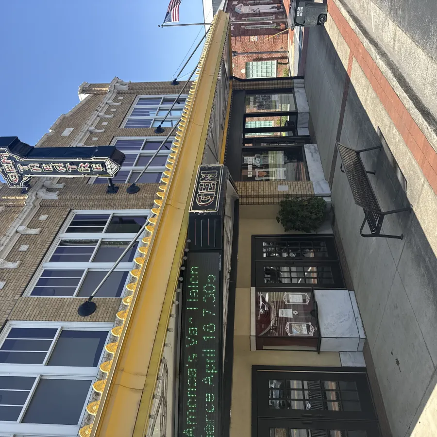 Historic Gem Theater with yellow awning and vintage marquee in sunny downtown street scene