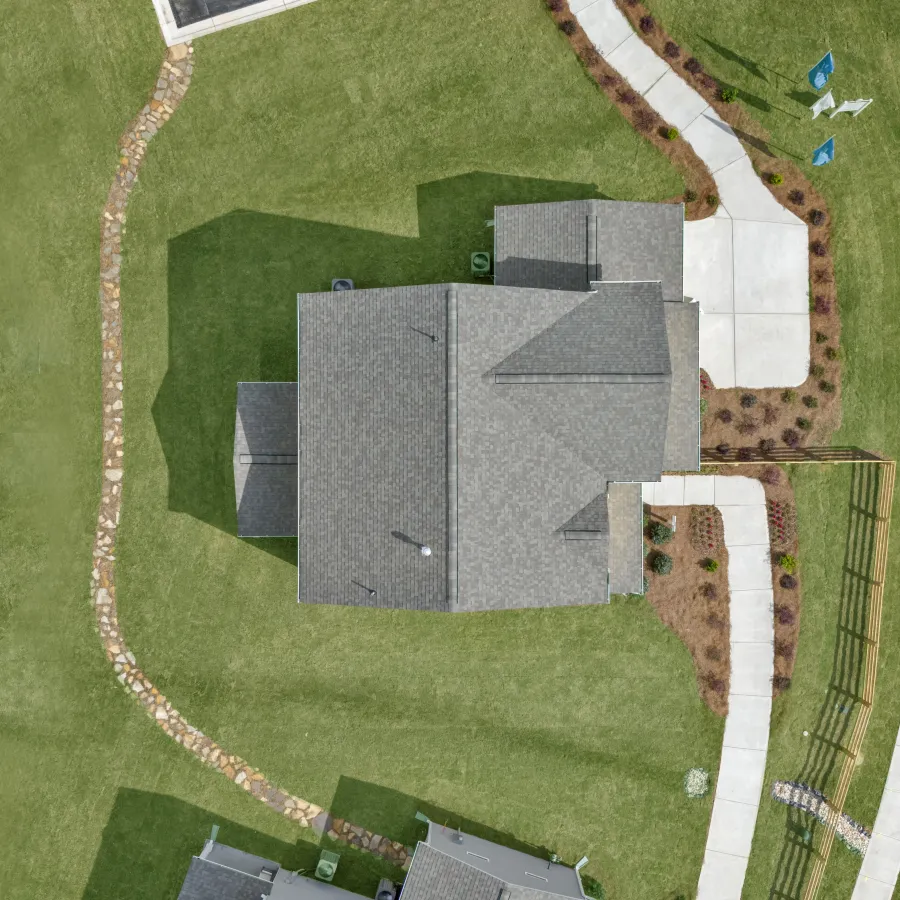 Aerial view of a modern house surrounded by landscaped green space and pathways.