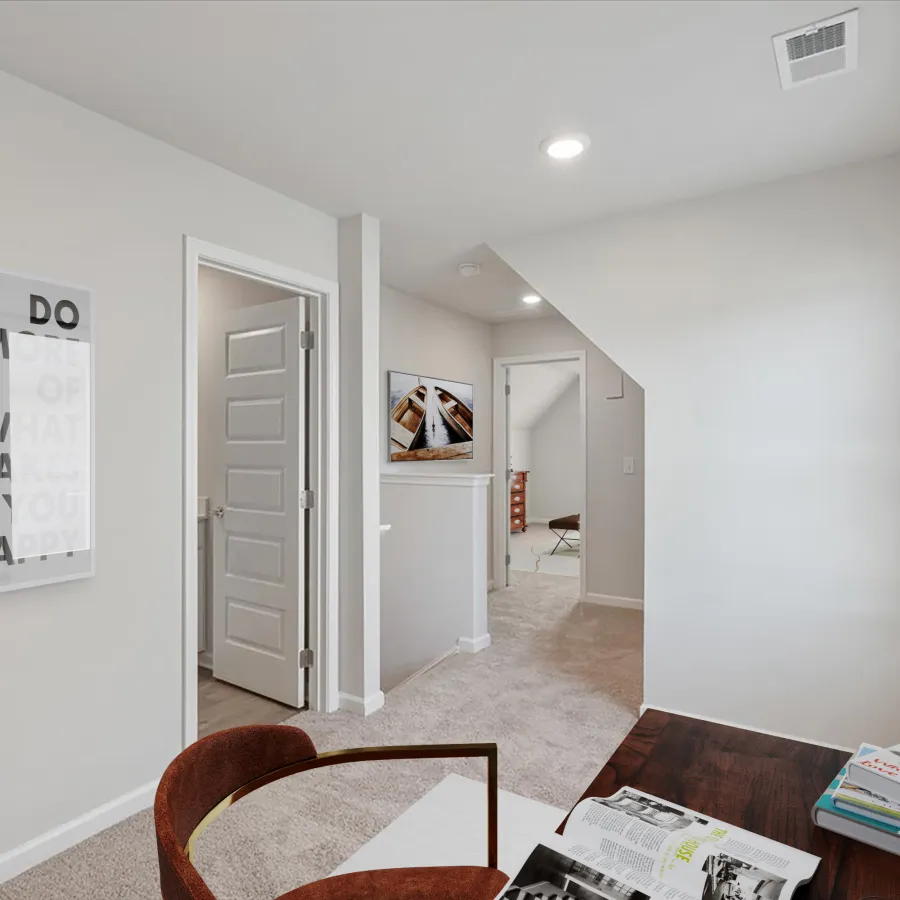 Modern bright hallway with beige carpet, white walls, open doors, motivational framed poster, and wooden desk with books.