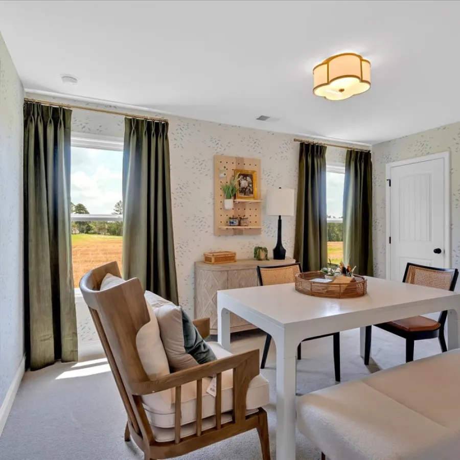 Bright modern dining room with white table, wooden chairs, bench seating, dark curtains, and patterned wallpaper.