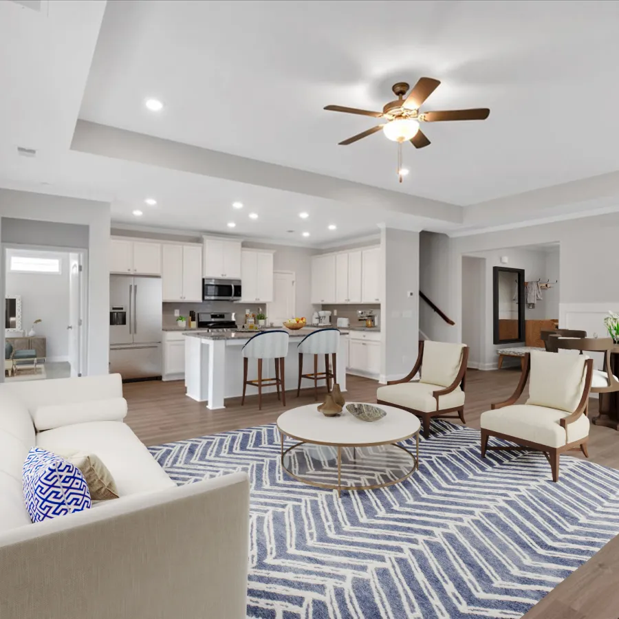 Open floor plan living room with white sofa, blue patterned rug, wooden chairs, modern kitchen, and dining area.