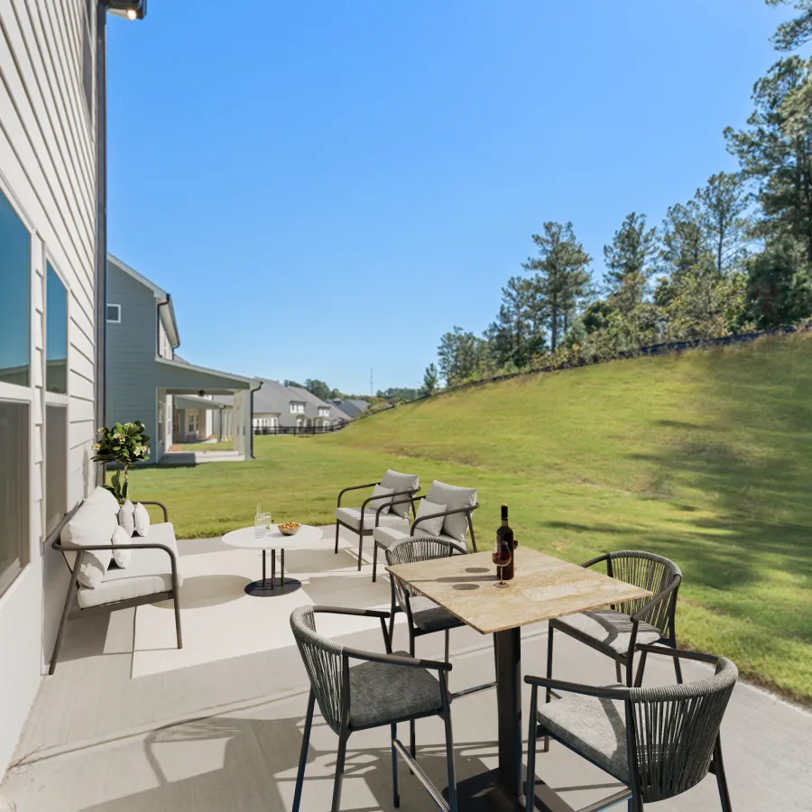 a patio with a table and chairs and a grassy yard with trees