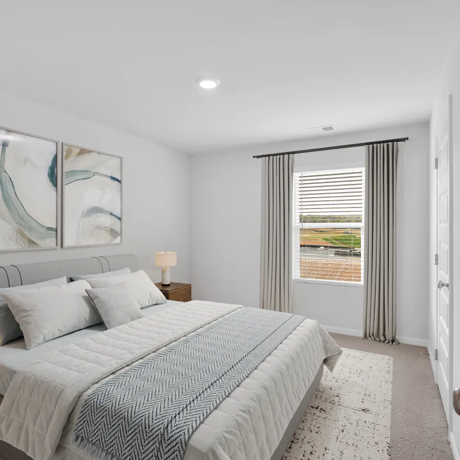 Modern bedroom featuring a queen bed, artwork, curtains, and natural light.
