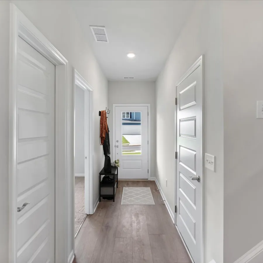 Bright modern hallway with white doors, light wood flooring, and a small entry table under a coat rack.