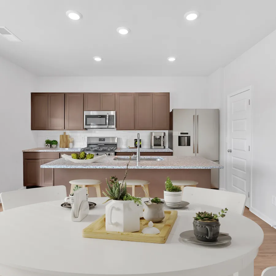 Modern kitchen with wooden cabinets, stainless steel appliances, and a dining area featuring a round table and plants.