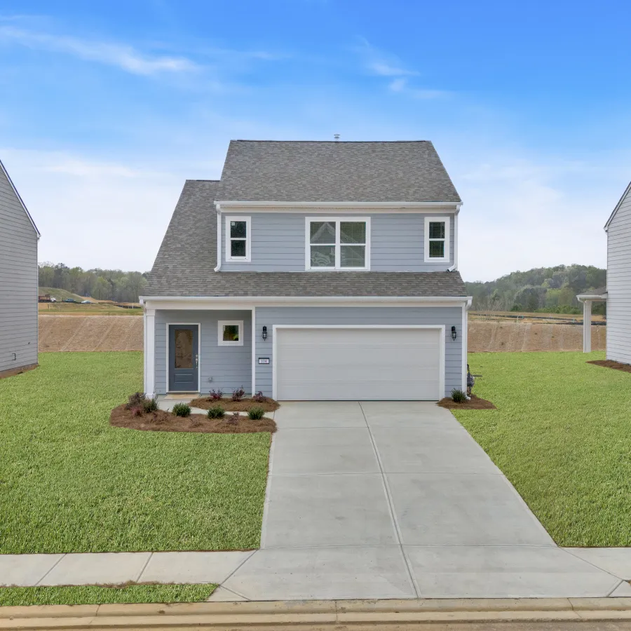Modern two-story gray house with a two-car garage and neatly landscaped front yard under a blue sky.