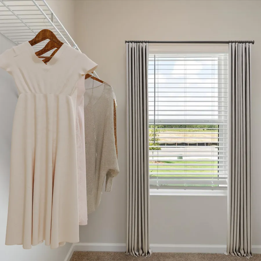 Light pink dresses and a beige sweater hanging on wooden hangers in a bright walk-in closet with window.