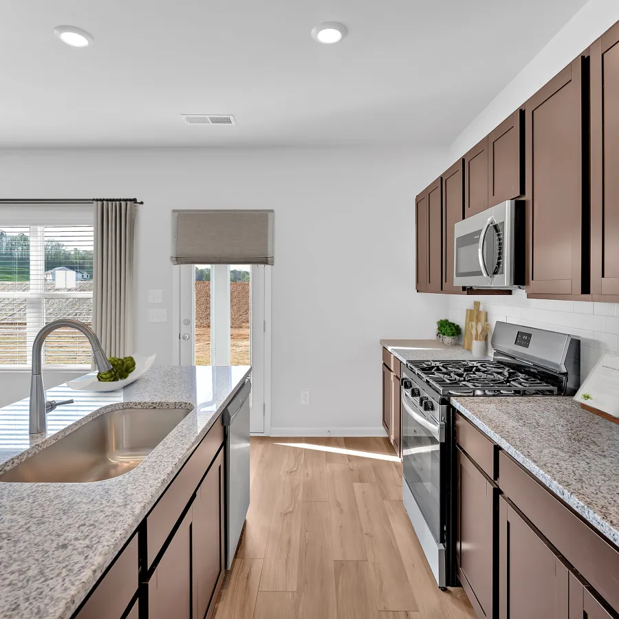 Modern kitchen with granite countertops, stainless steel appliances, and spacious layout in a bright setting.